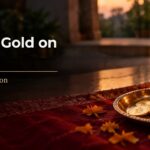 Why we buy gold on Dhanteras: gold coins & a gold chain on a brass plate beside a diya & marigolds