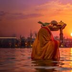 Chhath Puja 2026 devotees offering Sandhya Arghya with bamboo soop trays to the setting sun in a river